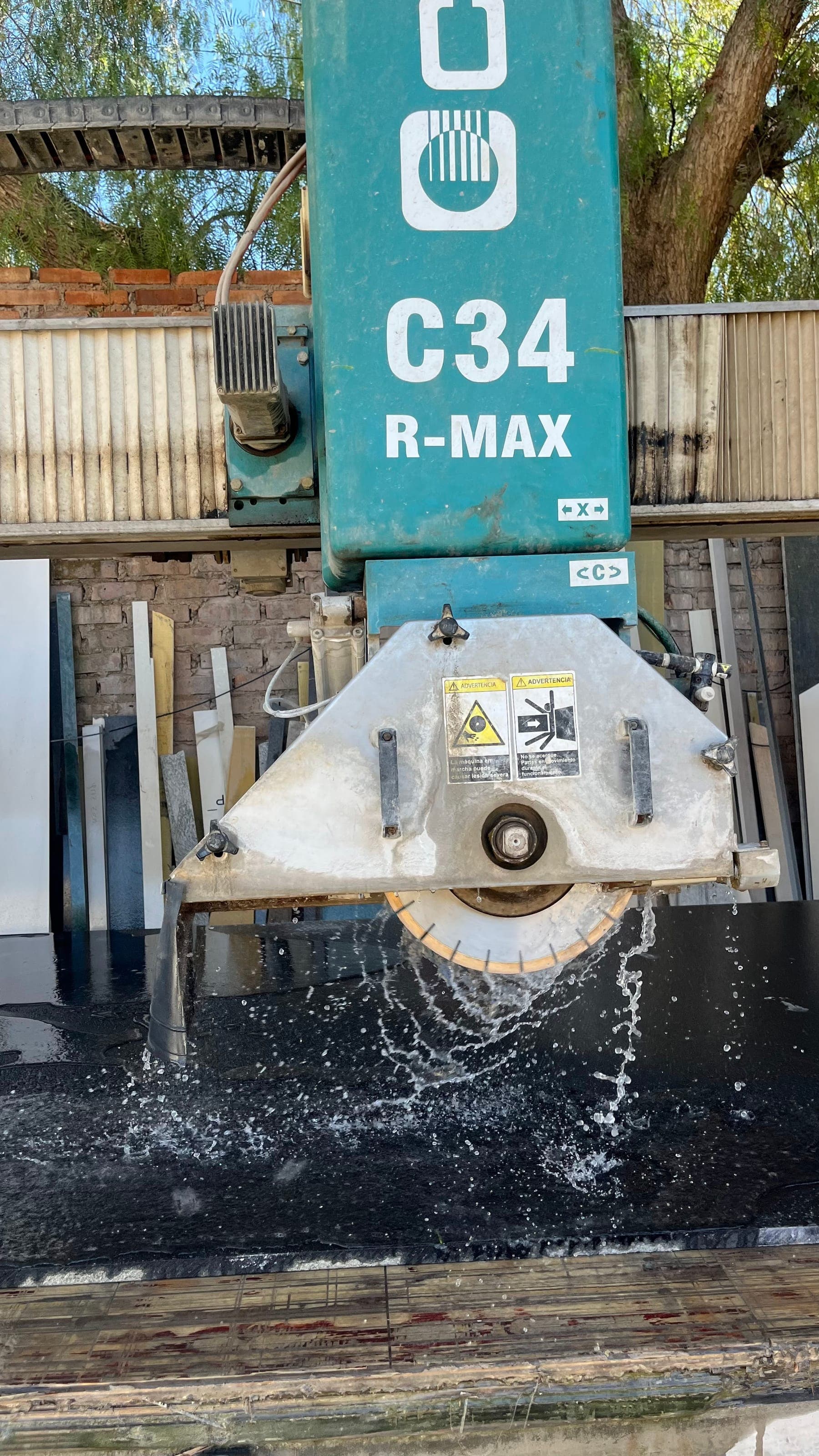 Disco de la cortadora de puente cortando una placa de piedra con agua en el taller de Puro Mármol