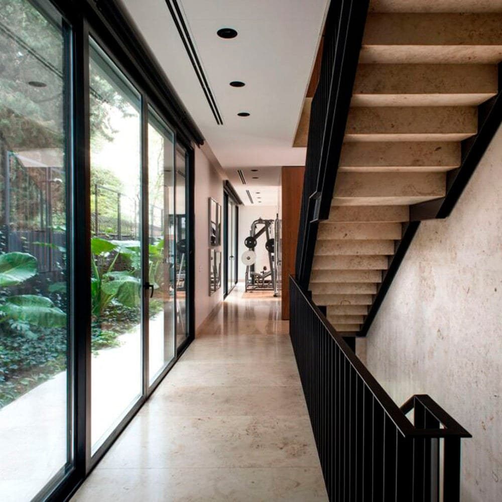 Pasillo interior con piso de Jura Beige y escalera de chapa plegada