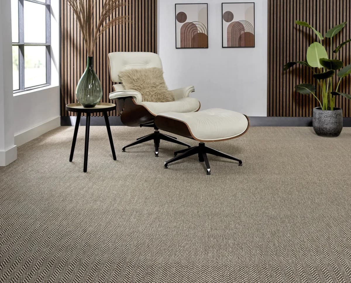 Ambiente con alfombra de pared a pared en tejido plano, sillón de cuero claro y pared de listones de madera