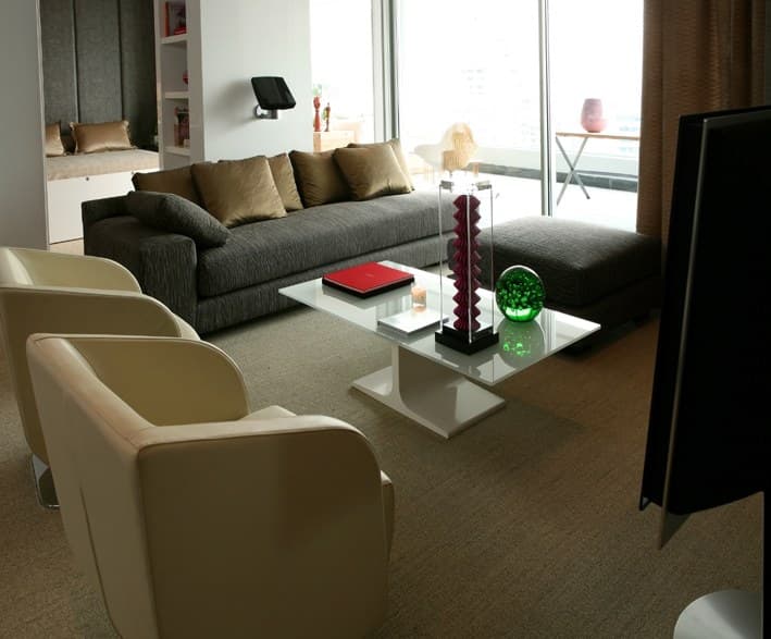 Living con alfombra de lana de pared a pared, sillones claros y ventanal