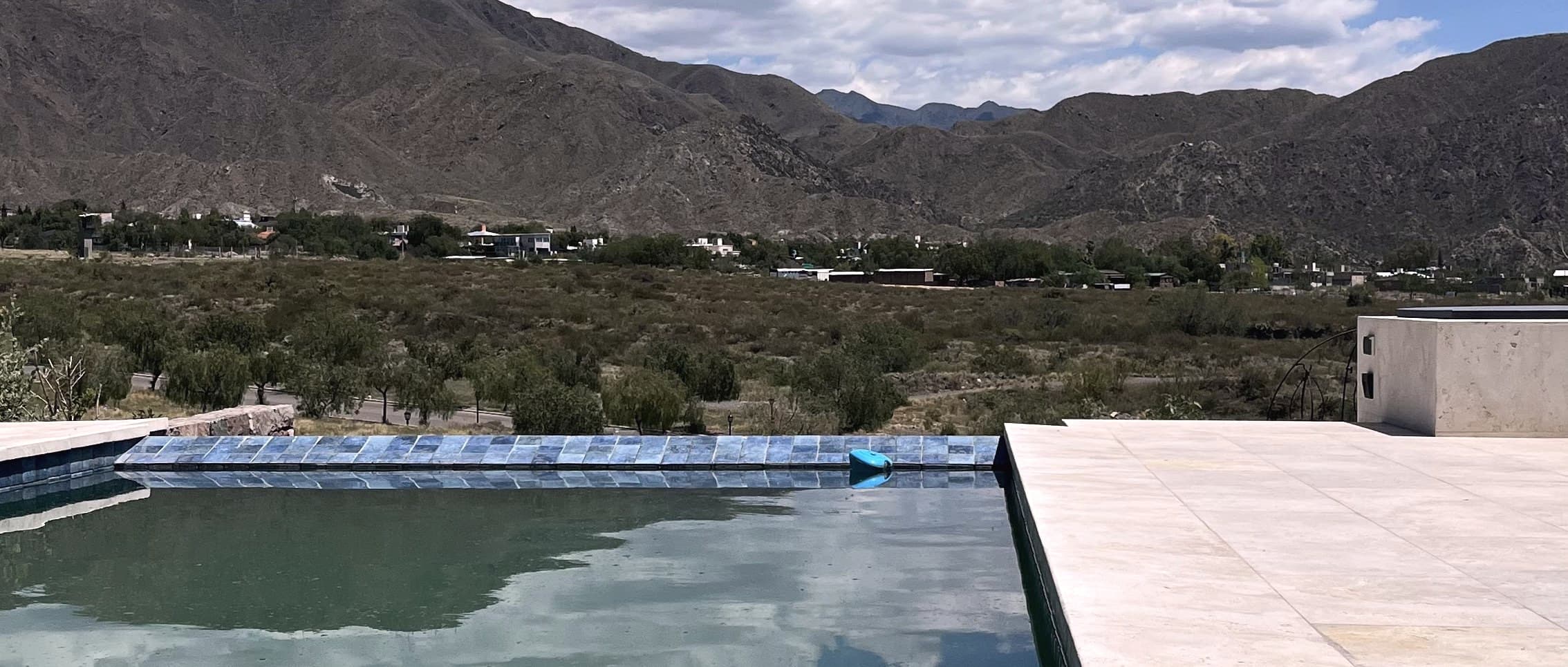 Pileta con solado de travertino nacional y la precordillera de fondo