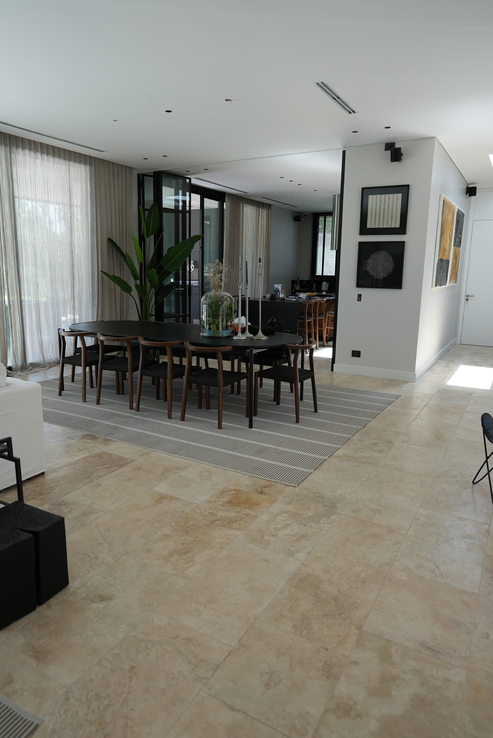 Comedor con piso de travertino en placas grandes y ventanales al jardín