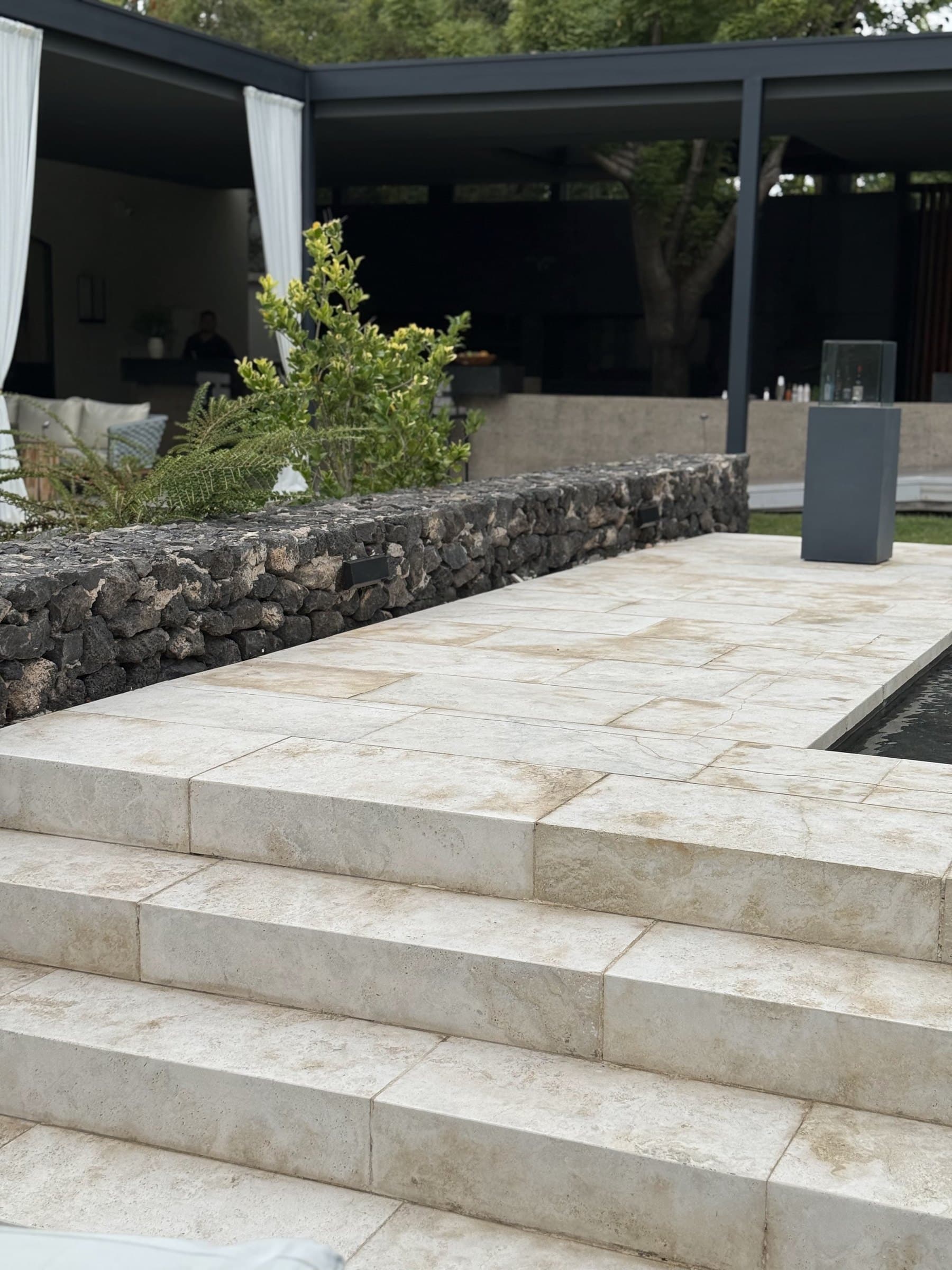 Escalinata y patio en placas de travertino que bajan hacia una pileta