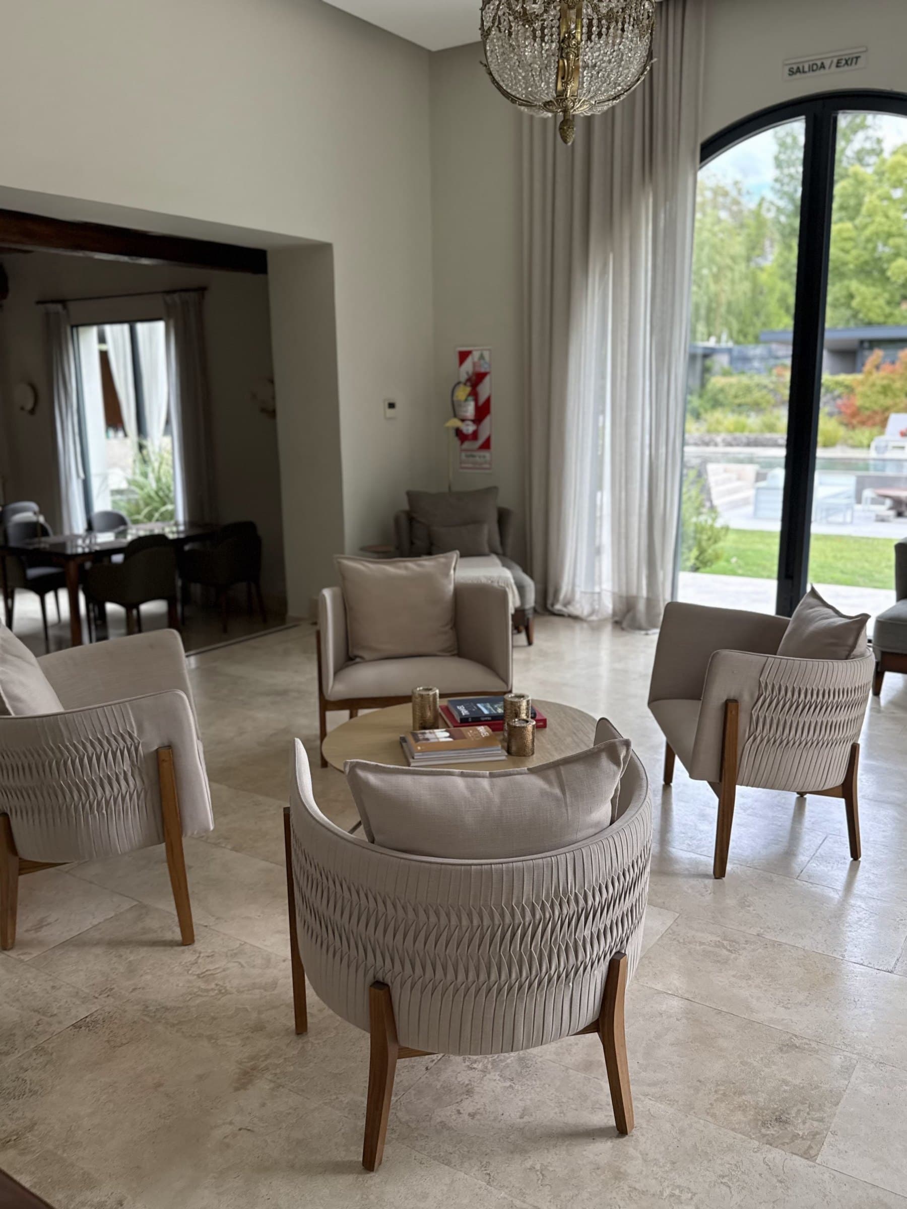 Living con piso de travertino y puertas de arco abiertas al jardín