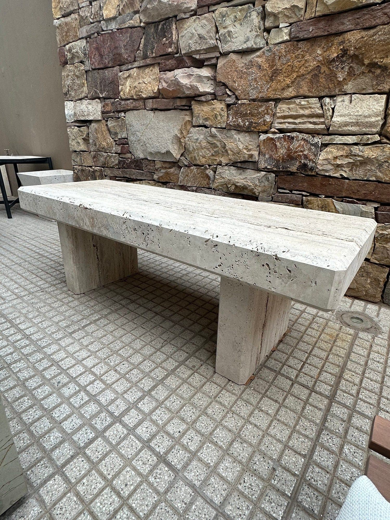 Banco macizo de travertino contra una pared de piedra